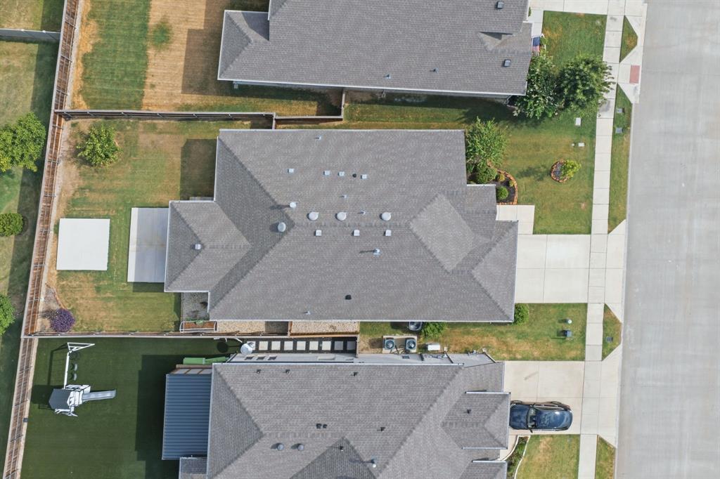 709 Bent Brook Road Oak Point, TX 75068 - Photo 18 of 20 Gable roofline residential property featuring a paved driveway, concrete patio, and a grassed backyard