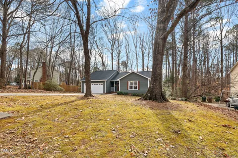 a view of house with yard and trees in the background