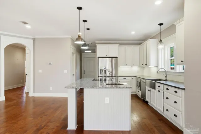 a large kitchen with kitchen island white cabinets and stainless steel appliances