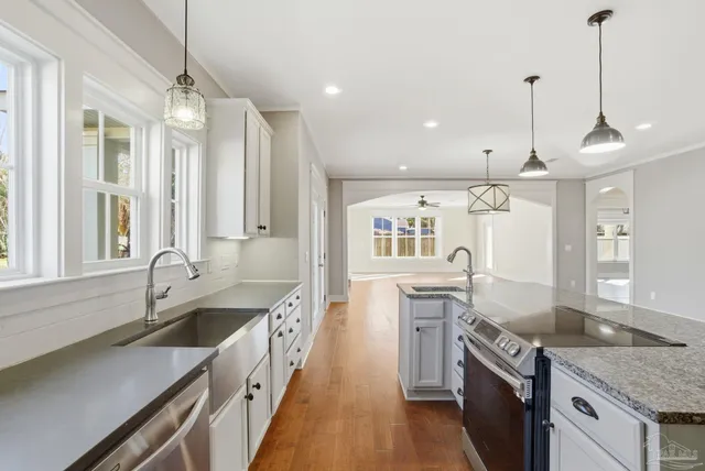 a kitchen with granite countertop a sink stove and refrigerator