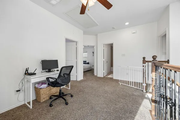 a view of a workspace with furniture and a ceiling fan