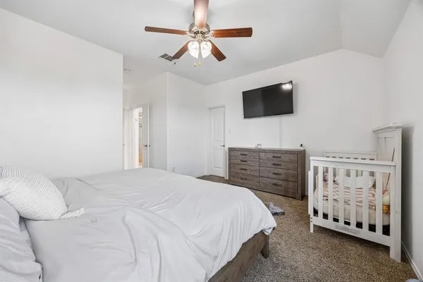 a bedroom with a bed a flat tv screen and a dresser