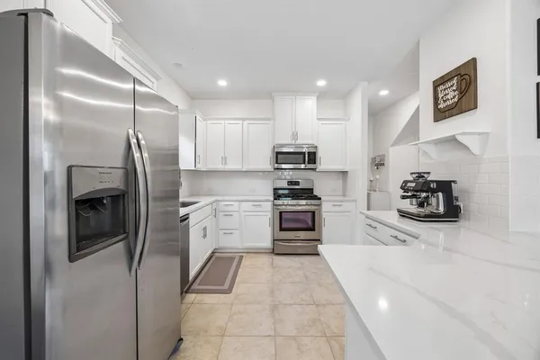a kitchen with stainless steel appliances kitchen island granite countertop a refrigerator and a stove top oven