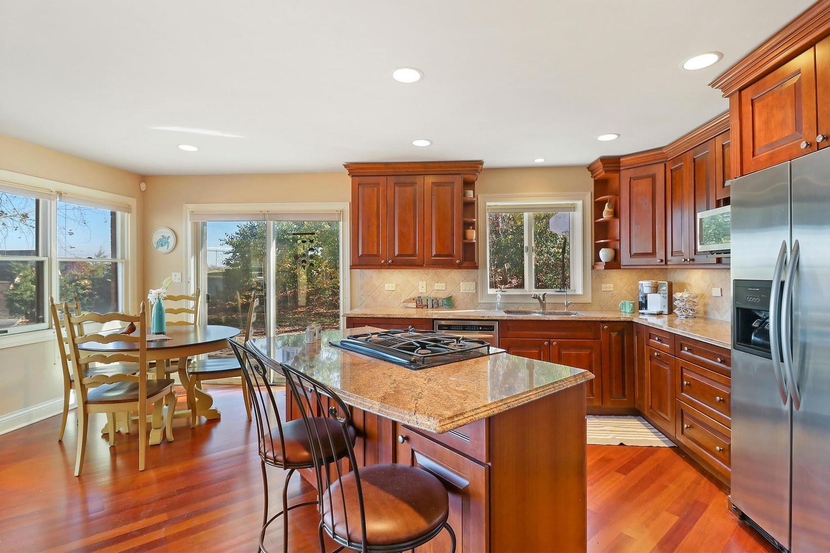 1004 Pistakee View Drive Johnsburg, IL 60051 - Photo 52 of 74 a kitchen with stainless steel appliances granite countertop a stove a refrigerator a sink a dining table and chairs with wooden floor