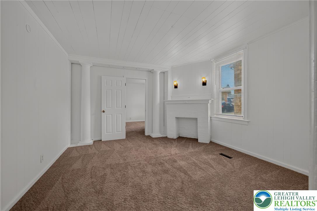 313 Main Street Slatington, PA 18080 - Photo 11 of 73 A cozy living space features an ornamental fireplace, plush carpet, and natural illumination from a large window.