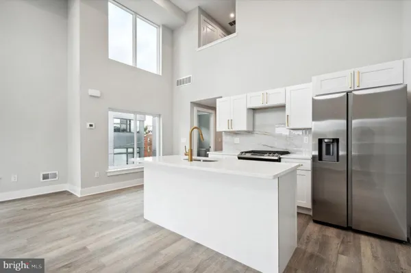 a kitchen with stainless steel appliances granite countertop a refrigerator a stove and white cabinets with wooden floor