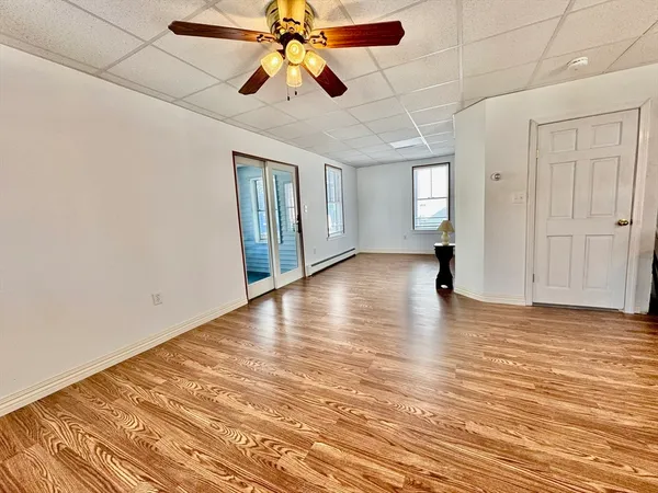 an empty room with wooden floor a ceiling fan and windows
