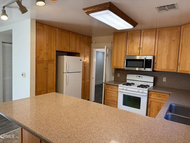 a kitchen with stainless steel appliances granite countertop a refrigerator stove top oven a sink and dishwasher