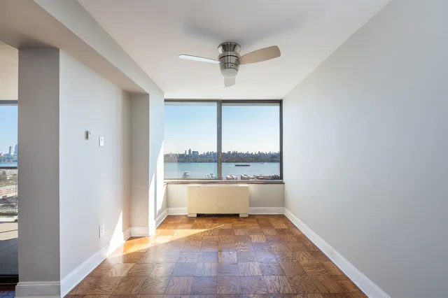 a view of empty room with wooden floor and fan