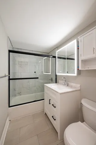 a bathroom with a granite countertop sink mirror vanity and toilet