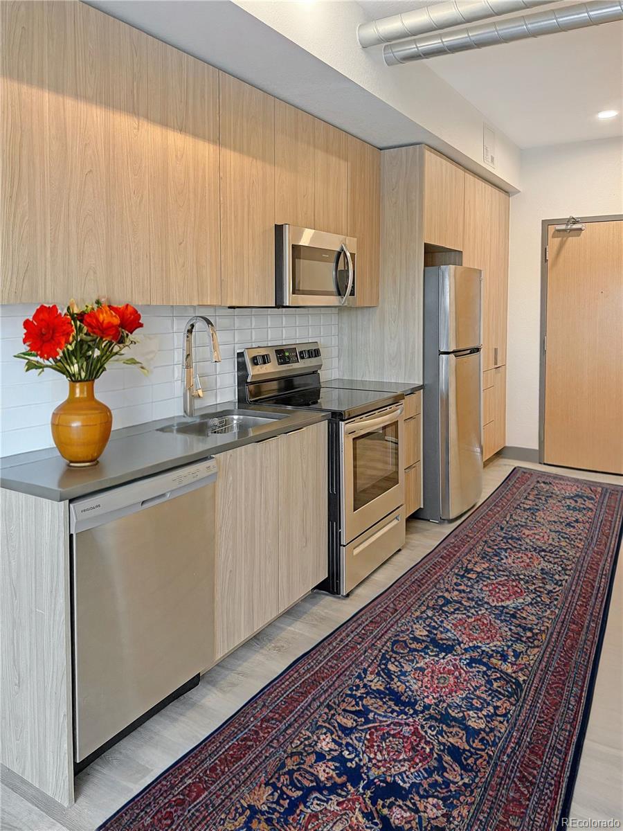 a kitchen with stainless steel appliances granite countertop a sink stove and refrigerator