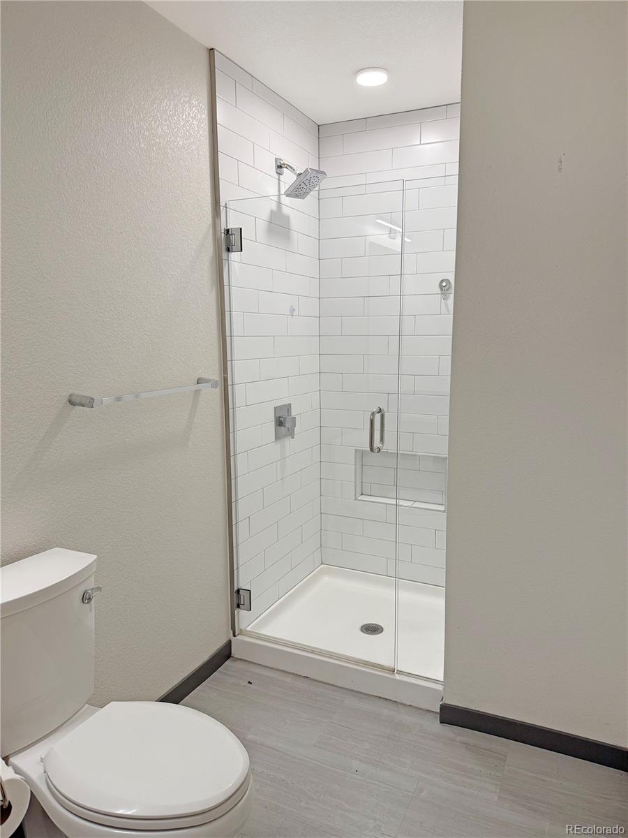 603 Inca Street, Unit 429 Denver, CO 80204 - Photo 11 of 16 a bathroom with a shower a toilet and a glass door
