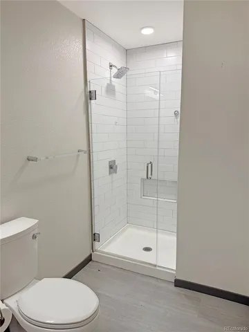 a bathroom with a shower a toilet and a glass door