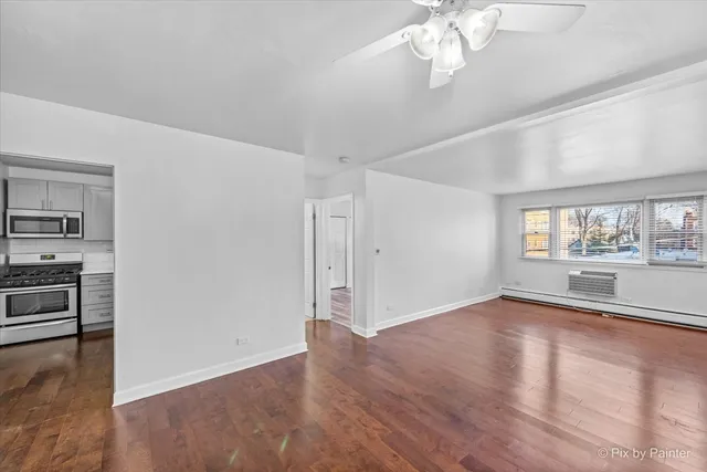 an empty room with wooden floor cabinet and windows
