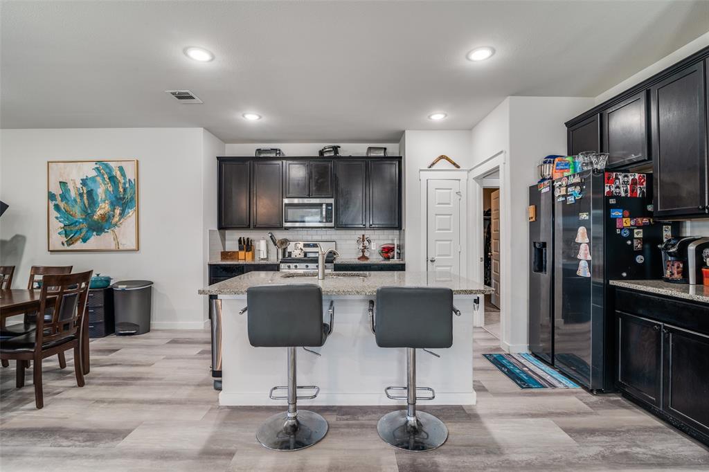 4204 Bullock Lane Forney, TX 75126 - Photo 10 of 25 a kitchen with stainless steel appliances kitchen island granite countertop a refrigerator and a stove top oven with wooden floor