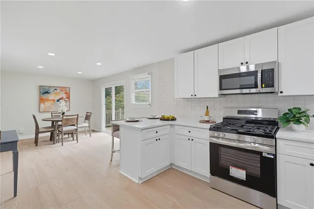 a kitchen with granite countertop a stove top oven a sink a dining table and chairs