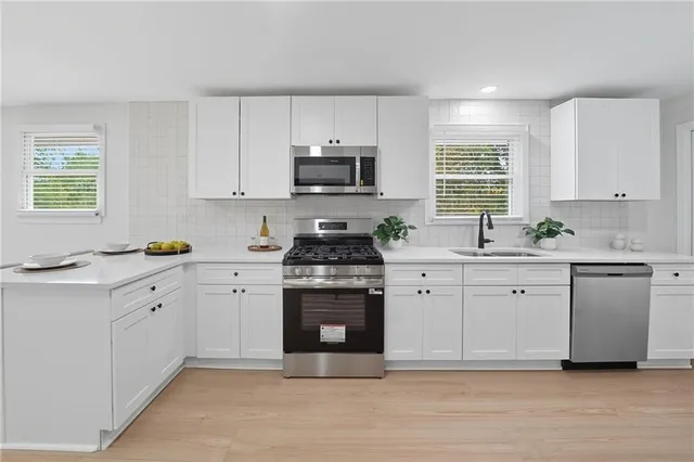 a kitchen with white cabinets sink and stainless steel appliances