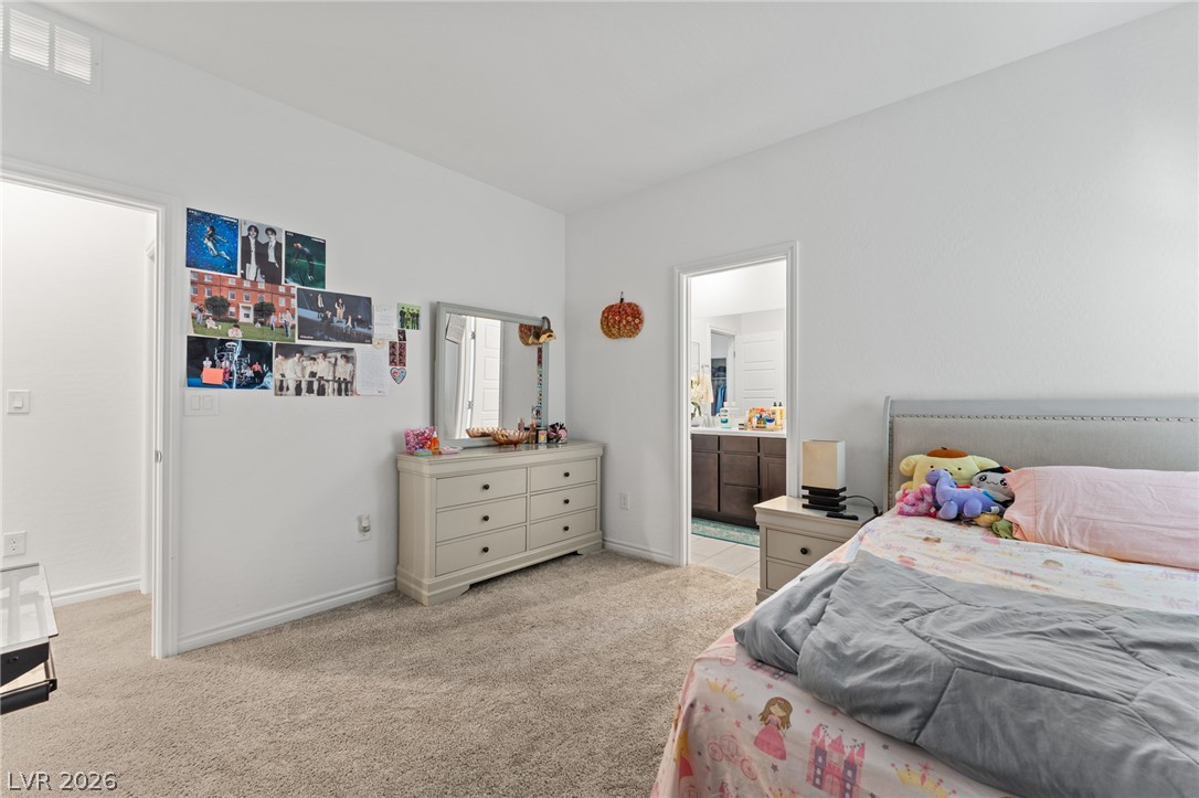 8879 Roadrunner Ravine Street Las Vegas, NV 89166 - Photo 27 of 39 Plush carpeting creates a serene atmosphere in this restful sleeping area, offering easy access to an adjoining bath.