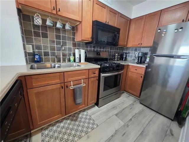 a kitchen with stainless steel appliances granite countertop a refrigerator a stove a sink and a microwave