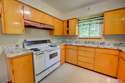 a kitchen with granite countertop cabinets stainless steel appliances a sink and a window