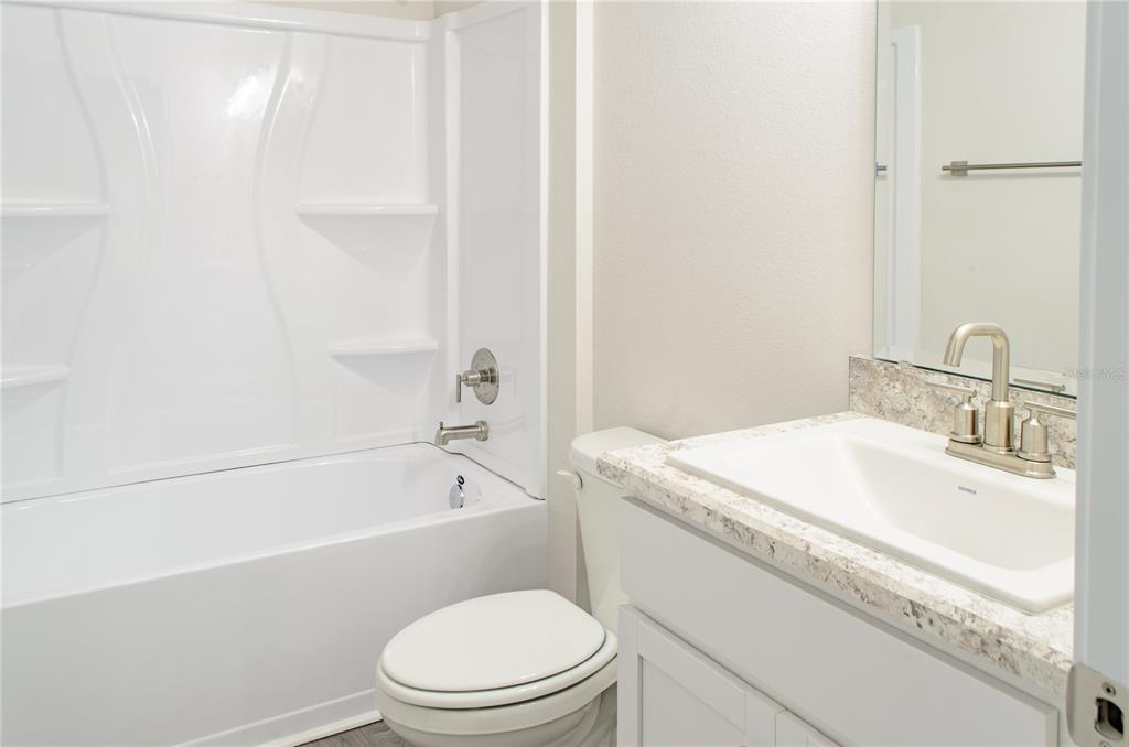 5 Red Clover Lane Palm Coast, FL 32164 - Photo 22 of 38 a bathroom with a granite countertop toilet a sink and a bathtub