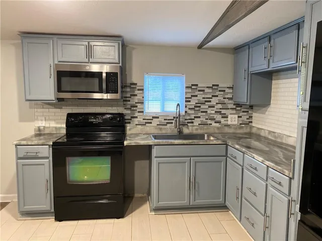 a kitchen with stainless steel appliances granite countertop a stove a microwave and a sink