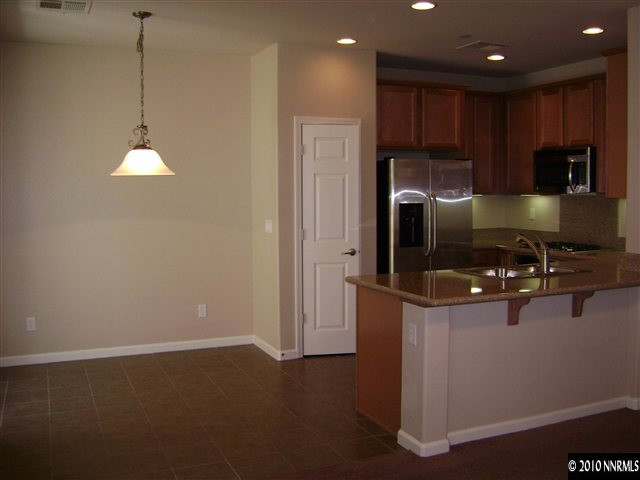 1845 A Wind Ranch Road Reno, NV 89521 - Photo 3 of 9 a kitchen with stainless steel appliances granite countertop a refrigerator a stove and a sink with wooden floor