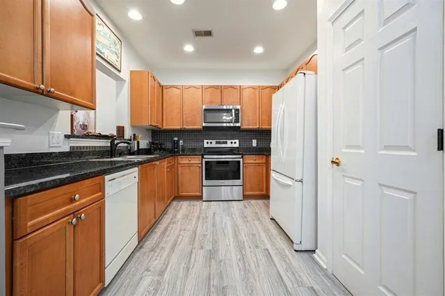a kitchen with stainless steel appliances granite countertop a stove a sink and a refrigerator