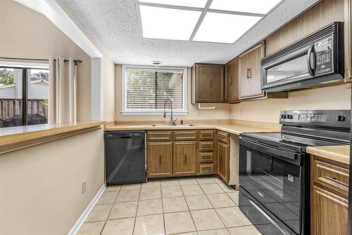 2976 Kin Cove, Unit 2976 Memphis, TN 38119 - Photo 11 of 24 Functional kitchen featuring wood-finish cabinetry, tile flooring, and integrated black appliances