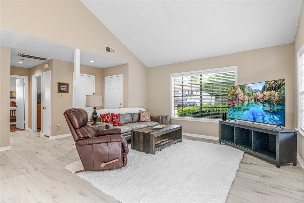 2976 Kin Cove, Unit 2976 Memphis, TN 38119 - Photo 6 of 24 Spacious living area featuring vaulted ceilings, light-tone wood-finish flooring, and multiple entryways