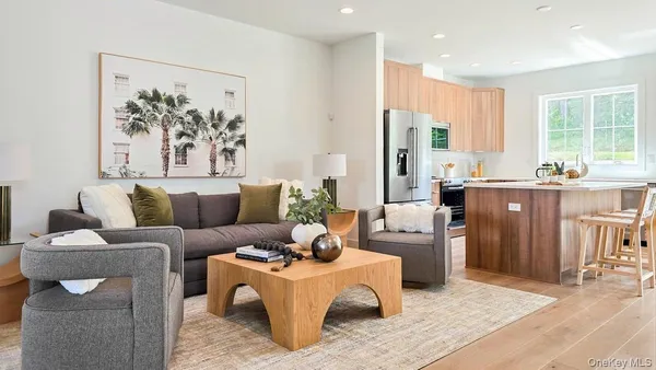 a living room with furniture a large window and stainless steel appliances