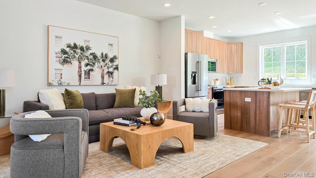 a living room with furniture a large window and stainless steel appliances