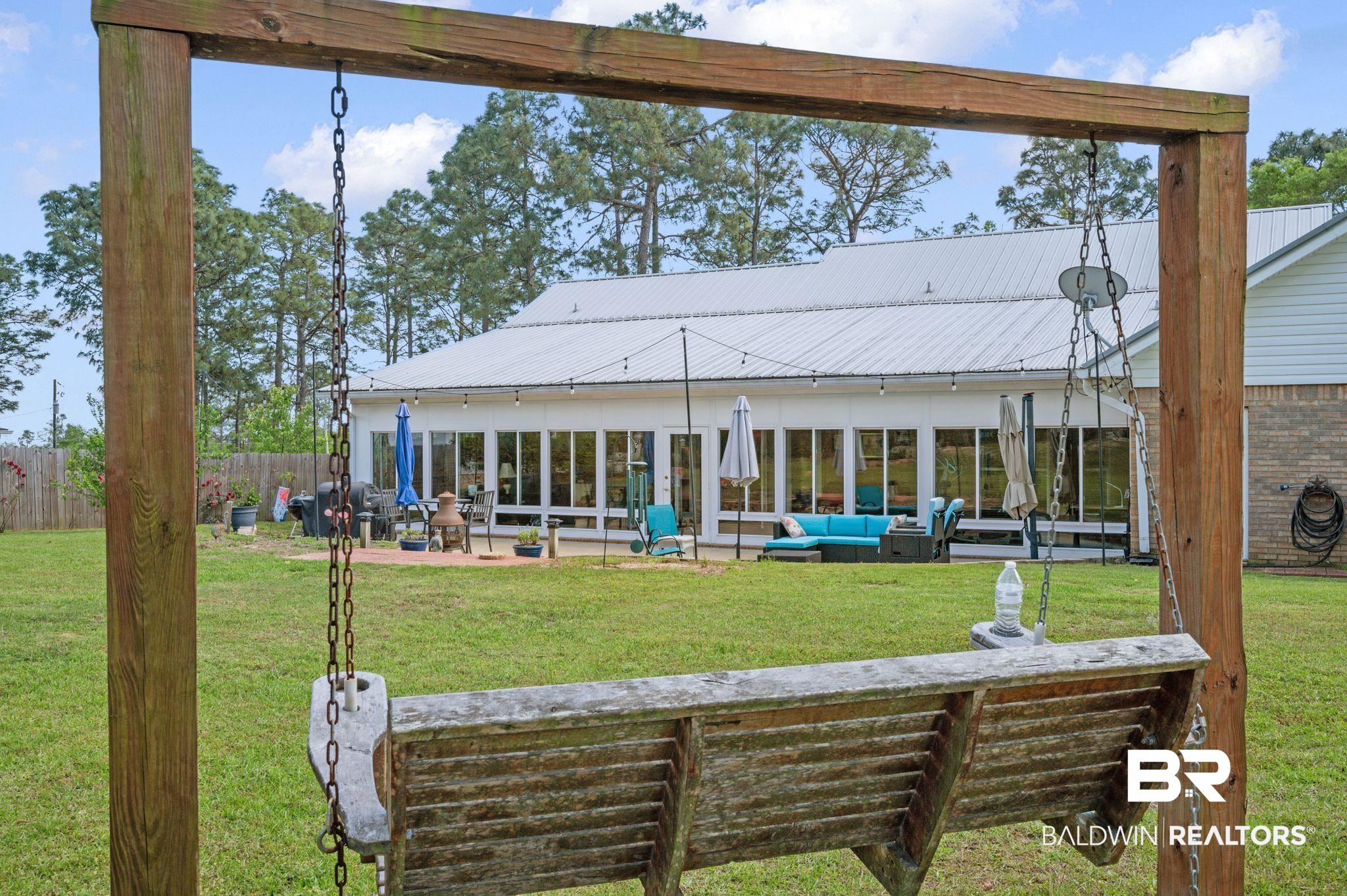 3100 Radcliff Road Saraland, AL 36571 - Photo 43 of 65 Back of property with an outdoor living space, a yard, metal roof, a patio area, and fence