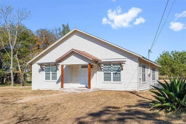 a view of a house with a yard and potted plants