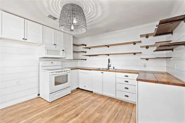 a kitchen with granite countertop a white stove top oven and cabinets