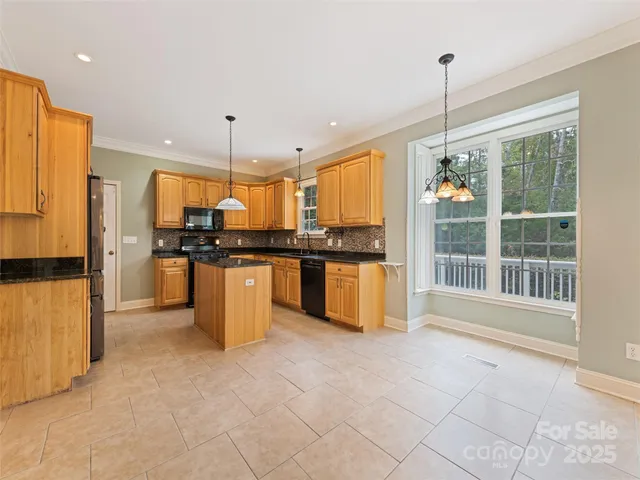 a kitchen with stainless steel appliances kitchen island granite countertop a refrigerator a oven a sink and a granite counter tops