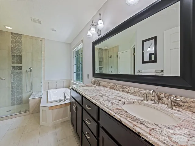 a bathroom with a granite countertop double vanity sink and a bathtub