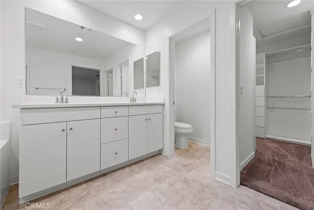 a spacious bathroom with a double vanity sink a mirror and a toilet