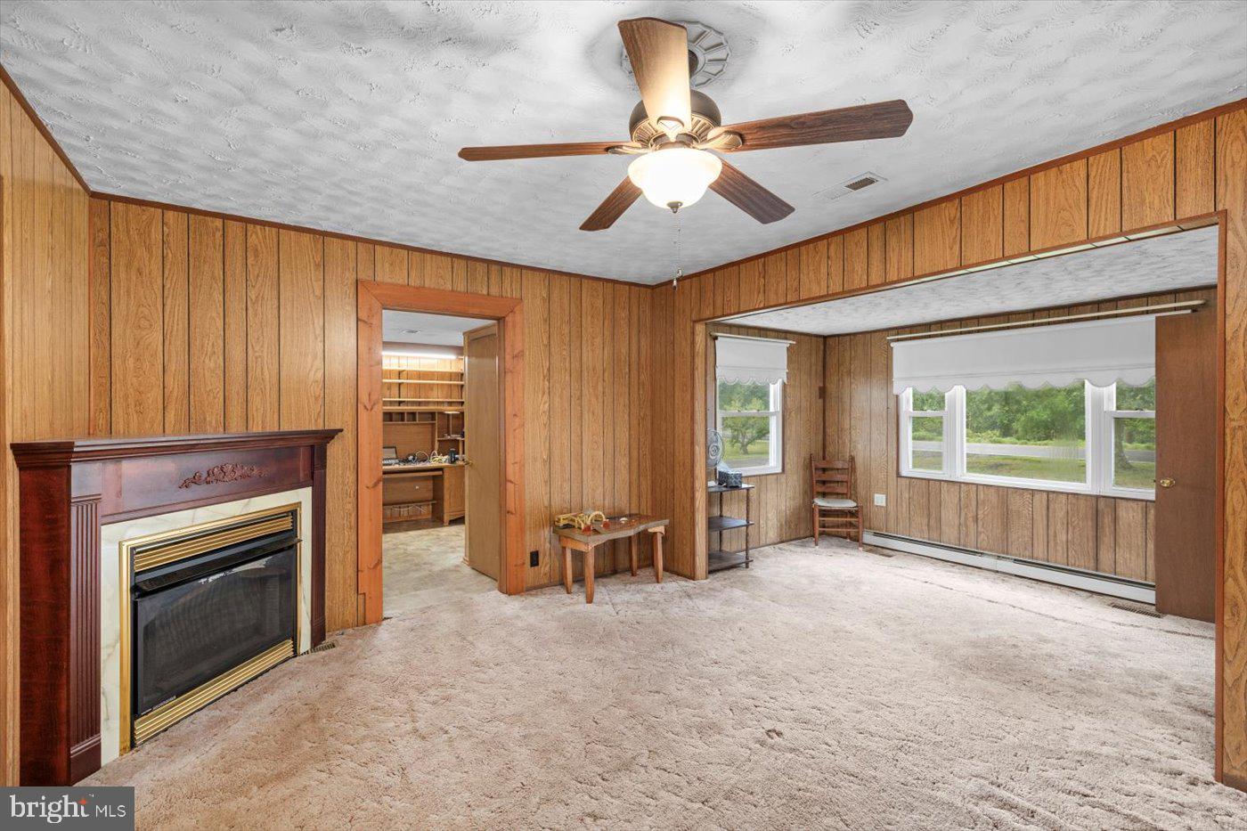 110 Longfield Road Colonial Beach, VA 22443 - Photo 13 of 40 an empty room with windows chandelier fan and a fireplace