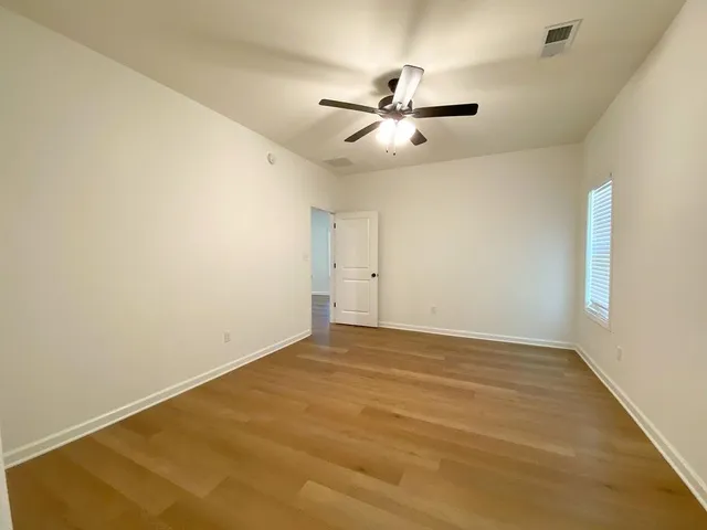 an empty room with windows and fan