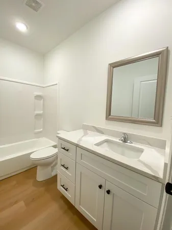 a bathroom with a granite countertop sink a toilet and bathtub