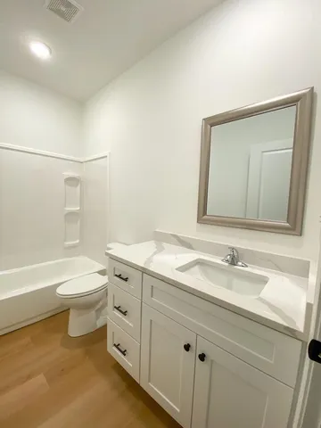 a bathroom with a granite countertop sink a toilet and bathtub