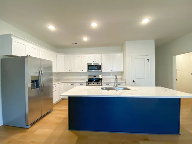 a large kitchen with kitchen island a sink stainless steel appliances and cabinets