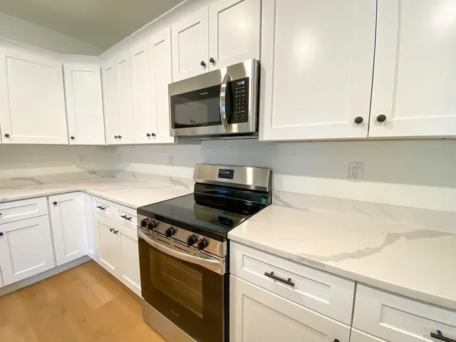 a kitchen with stainless steel appliances white cabinets and a stove a sink