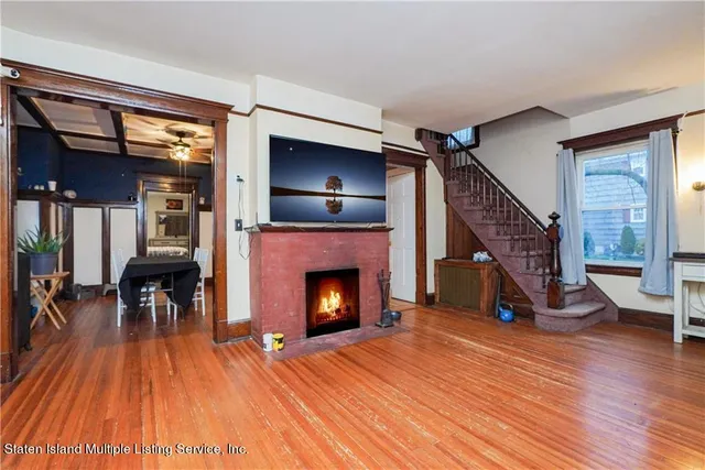 a view of an empty room with wooden floor fireplace and a window