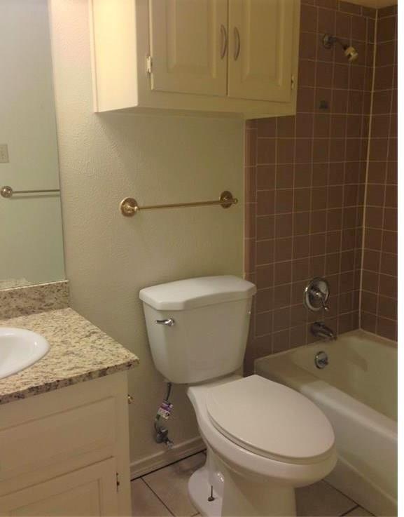 1720 Stonegate Drive Denton, TX 76205 - Photo 13 of 16 a bathroom with a granite countertop toilet a sink and bathtub