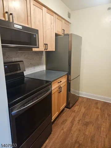 a kitchen with granite countertop a refrigerator and a microwave