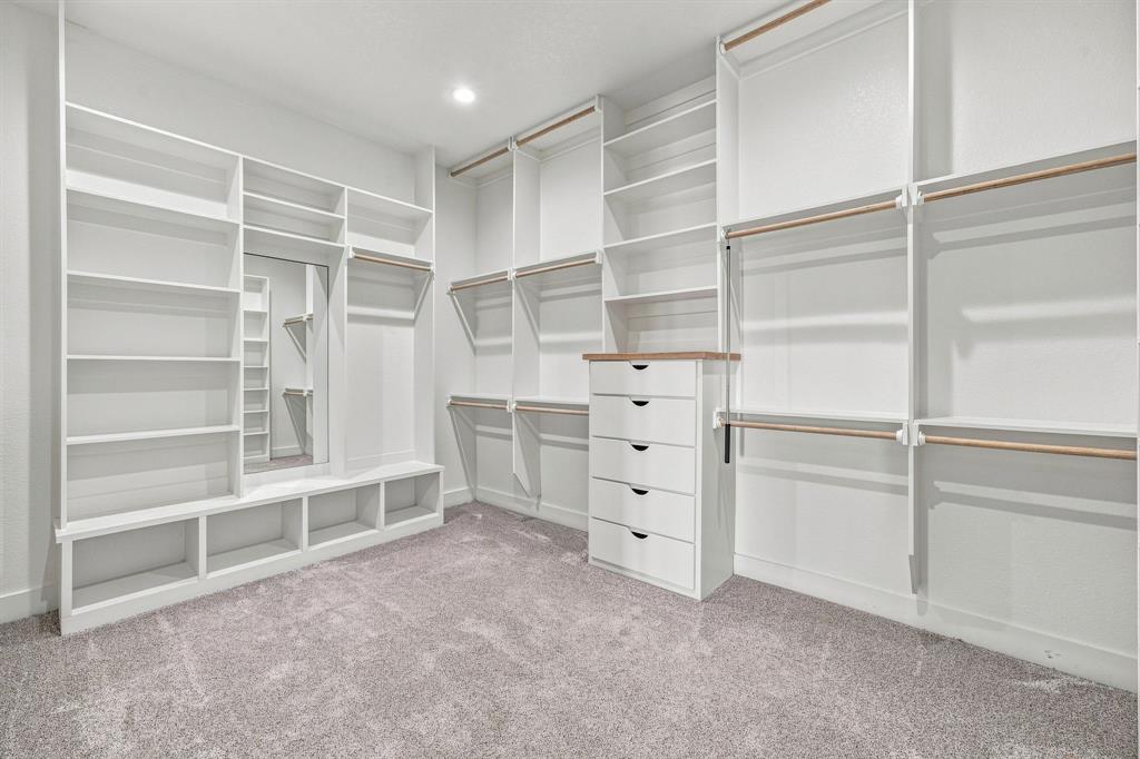 8140 Lavender Road Springtown, TX 76082 - Photo 22 of 40 Spacious walk-in closet featuring extensive built-in shelving, hanging rods, an integrated mirror, and a five-drawer dresser with a wood-finish top