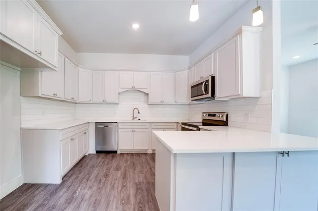 a kitchen with cabinets stainless steel appliances a sink and wooden floor