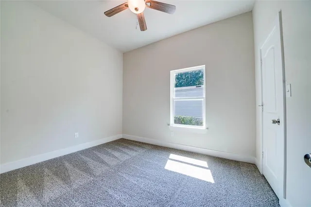 an empty room with a window and a ceiling fan